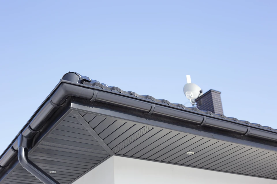 Extérieur d'une maison résidentielle montrant la toiture et les éléments de finition sous un ciel dégagé