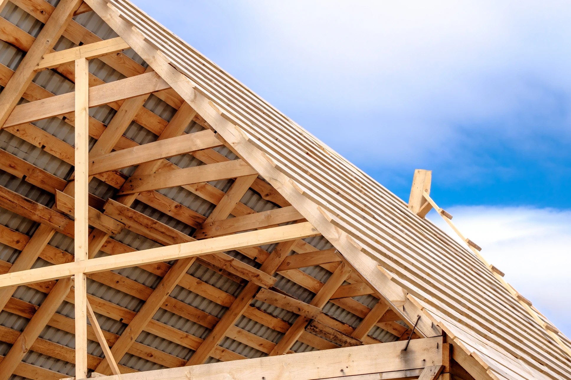 Chantier de construction d'une charpente en bois sous ciel bleu nuageux