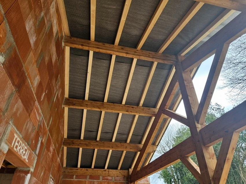 Intérieur d'un bâtiment en construction montrant la charpente en bois apparente vue du dessous
