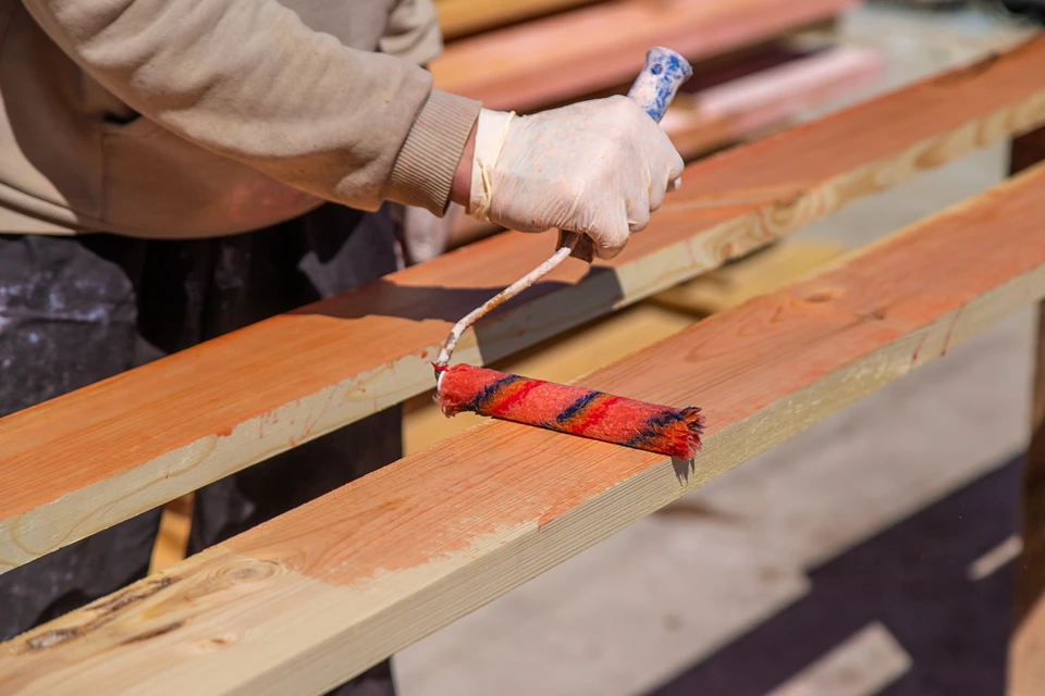 Équipe de charpentiers planifiant le bois à l'aide d'une machine, d'une femme et d'un homme