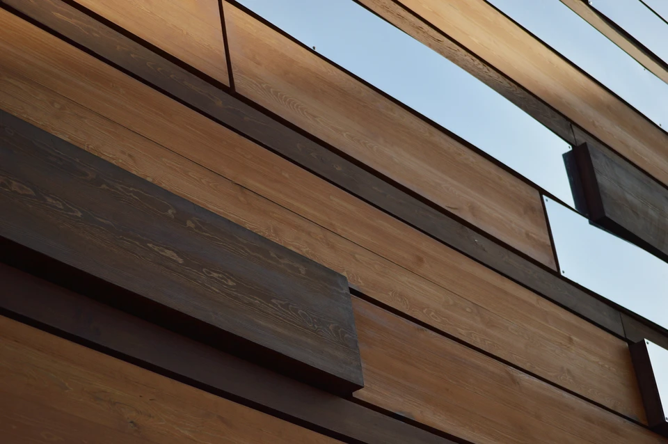 Façade extérieure en bardage bois vertical, lames de bois naturel disposées parallèlement avec joints creux réguliers