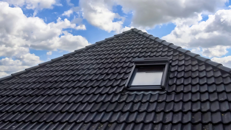 Charpentier travaillant dans les combles d'une maison en construction, agenouillé sur le plancher en cours d'installation
